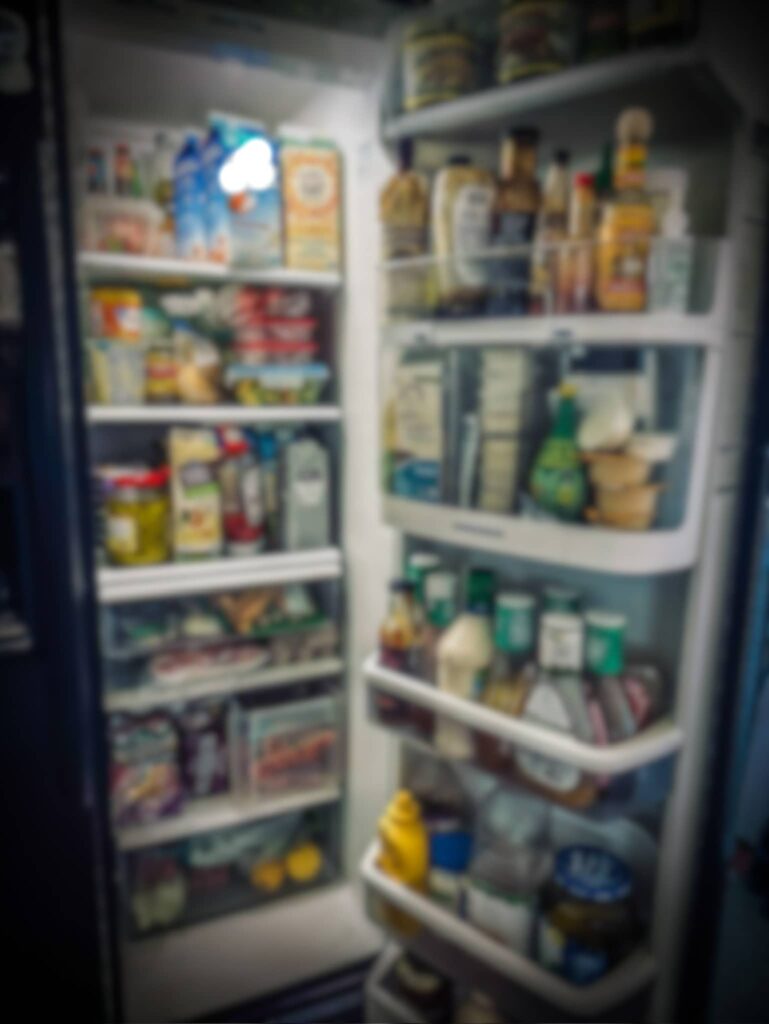 A very full refrigerator with blurred-out contents is in Sue Evergreen's kitchen.