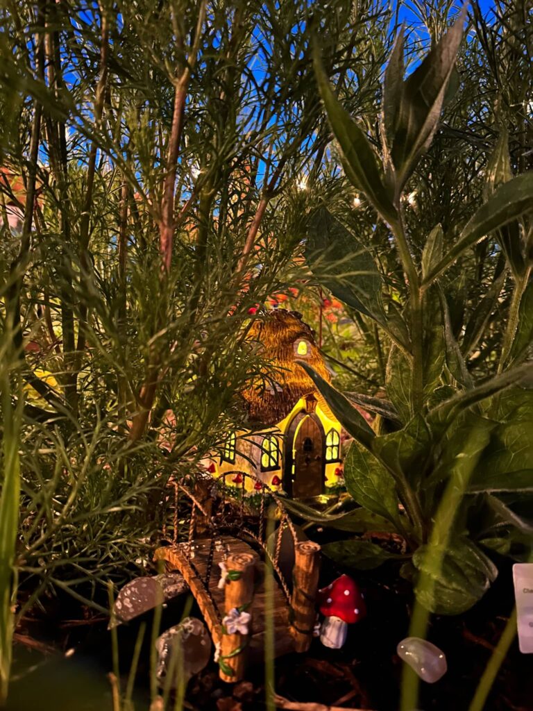 lit fairy house and bridge hidden in the cosmos at twilight in garden