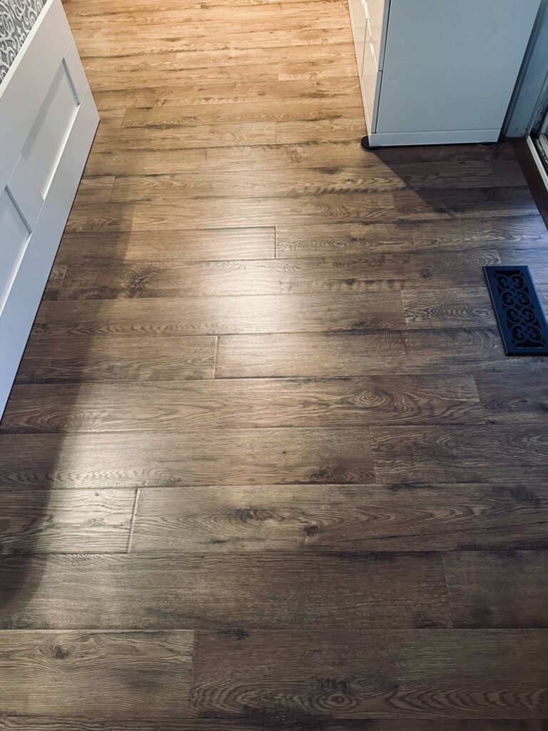 newly installed laminate floor with white furniture and black vent cover