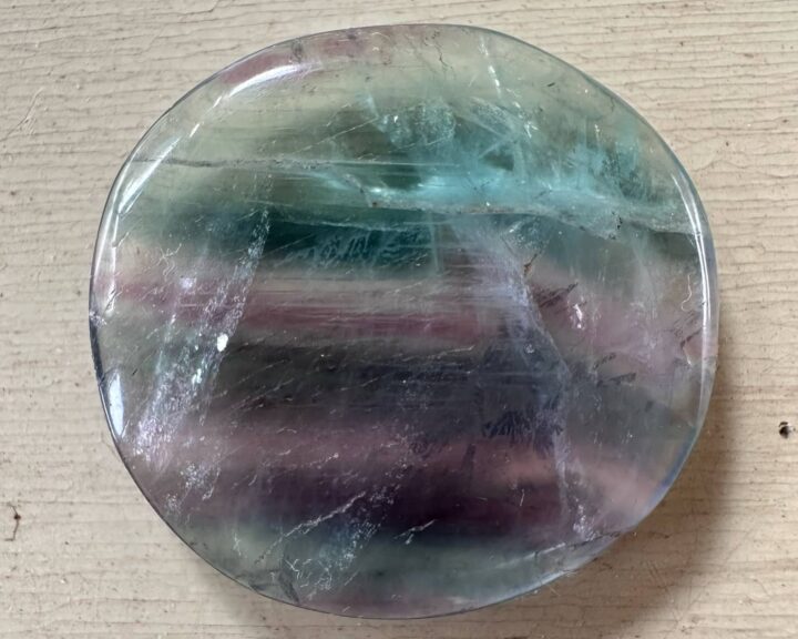 Round clear-looking pocket_rock with teal and purple striations.