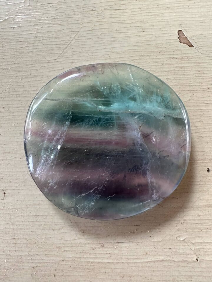 Round clear-looking pocket_rock with teal and purple striations.