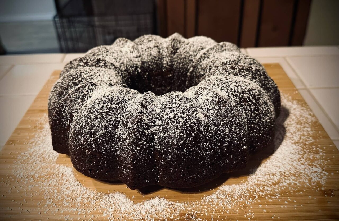 Vegan gingerbread cake formed in a bundt pan and sprinkled with powdered sugar posted in Today, I Suggest Cake by Sue Evergreen on Dropping Rocks.