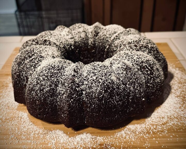 Vegan gingerbread cake formed in a bundt pan and sprinkled with powdered sugar posted in Today, I Suggest Cake by Sue Evergreen on Dropping Rocks.