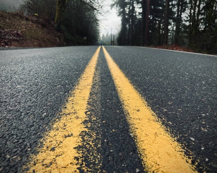 Looking down the solid yellow lines on a road with trees and mist in the background. Life's Magic on My Road, posted by Sue Evergreen.