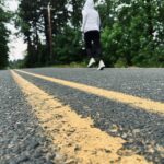 Sue is running down a road with trees all around. Posted in Why Do I Need To Run a Marathon on Dropping Rocks.