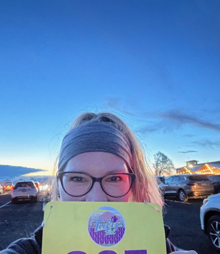 Sue Evergreen is holding her runner's badge at The Tulip Fest Half Marathon 2024.