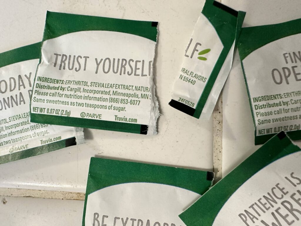A pile of empty stevia packets with messaging important to Sue Evergreen in a post about removing rocks for mindfulness.